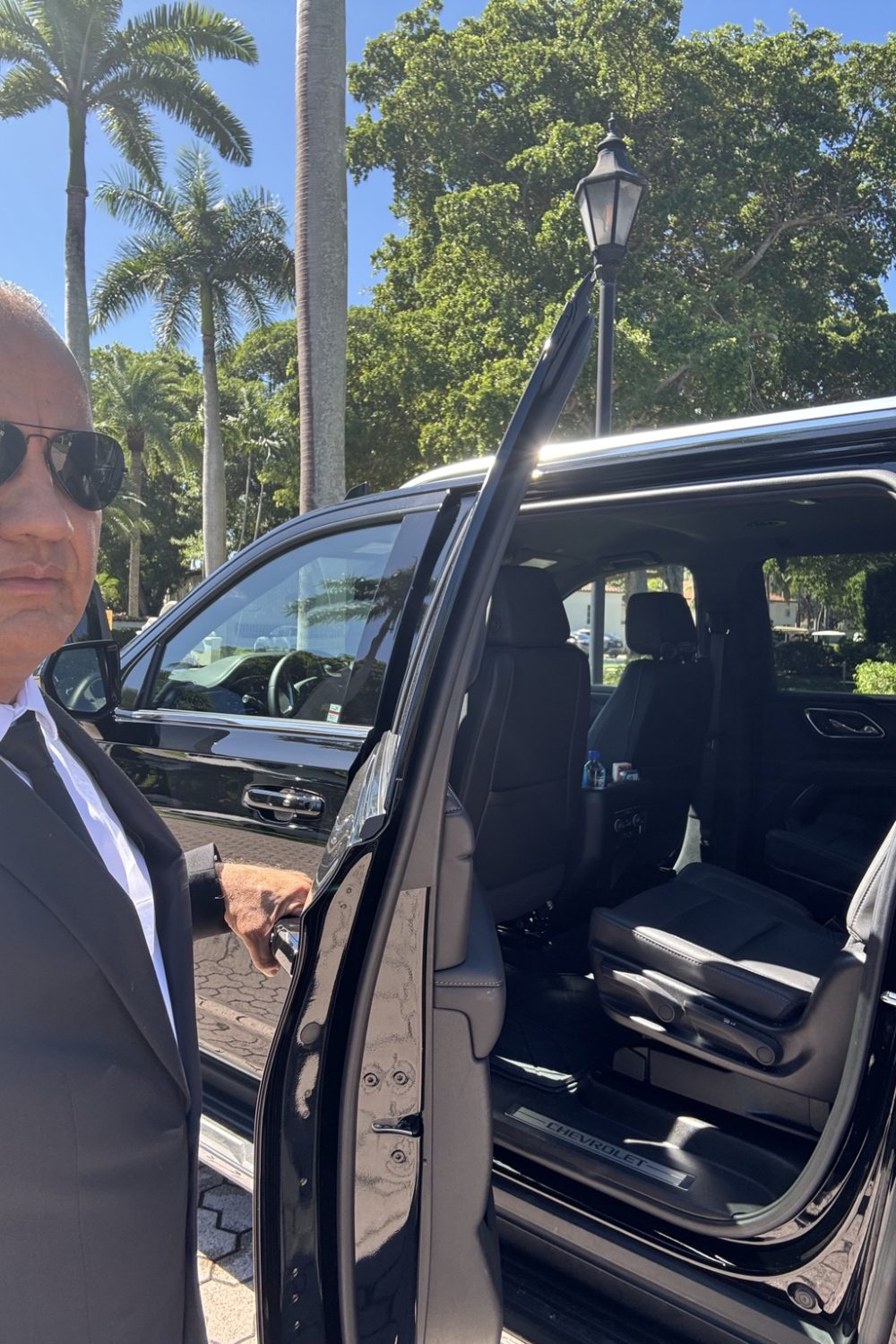 Professional chauffeur opening luxury SUV door in Miami – VIP Mega Limo service